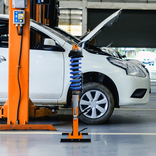 White car on an orange struttt lift in a garage
