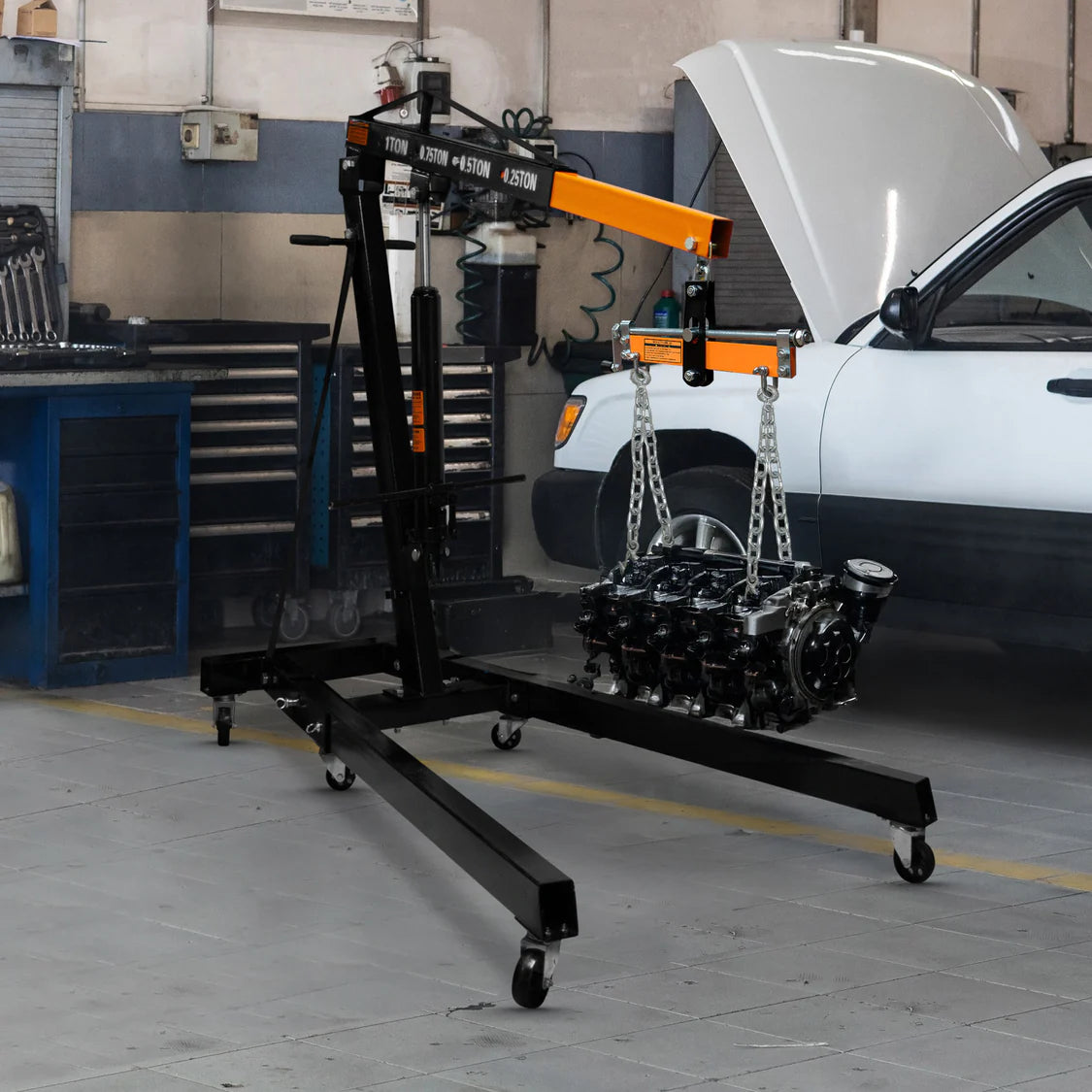 Engine hoist with a car engine on it in a garage setting